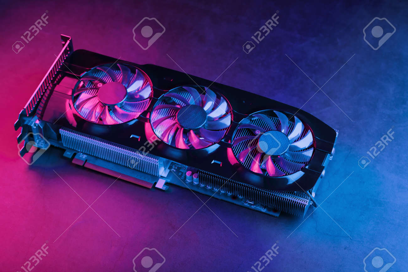 Large and powerful graphics card with three fans with blue pink light. The concept of a cyberpunk video chip for gaming and cryptocurrency mining. Dark key, top view - 169206456 Large and powerful graphics card with three fans with blue pink light. The concept of a cyberpunk video chip for gaming and cryptocurrency mining. Dark key, top view - 169206456