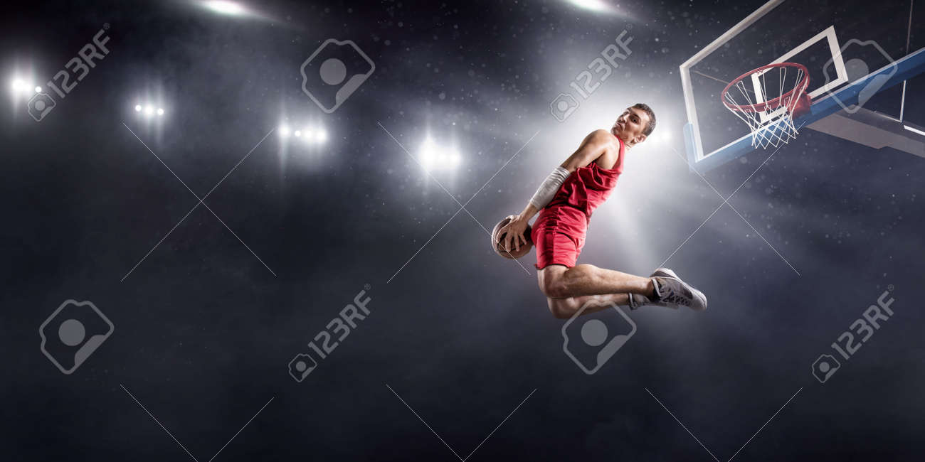 プロバスケットボールのアリーナでスラムダンクを作るバケトボール選手 彼は無ブランドの服を着ている の写真素材 画像素材 Image