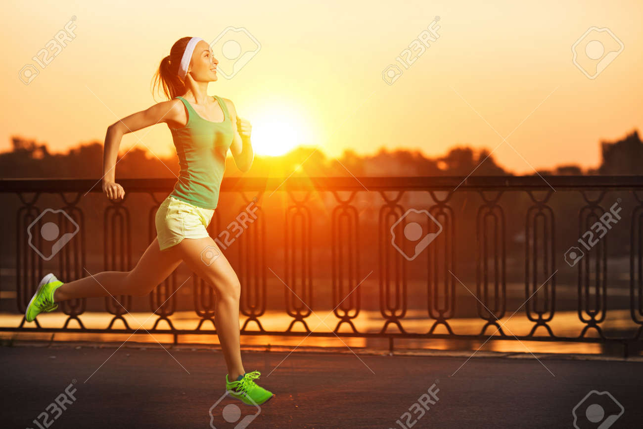 Running woman. Runner is jogging in sunny bright light on sunrise. Female fitness model training outside in the city on a quay. Sport lifestyle. - 32020349 Running woman. Runner is jogging in sunny bright light on sunrise. Female fitness model training outside in the city on a quay. Sport lifestyle. - 32020349