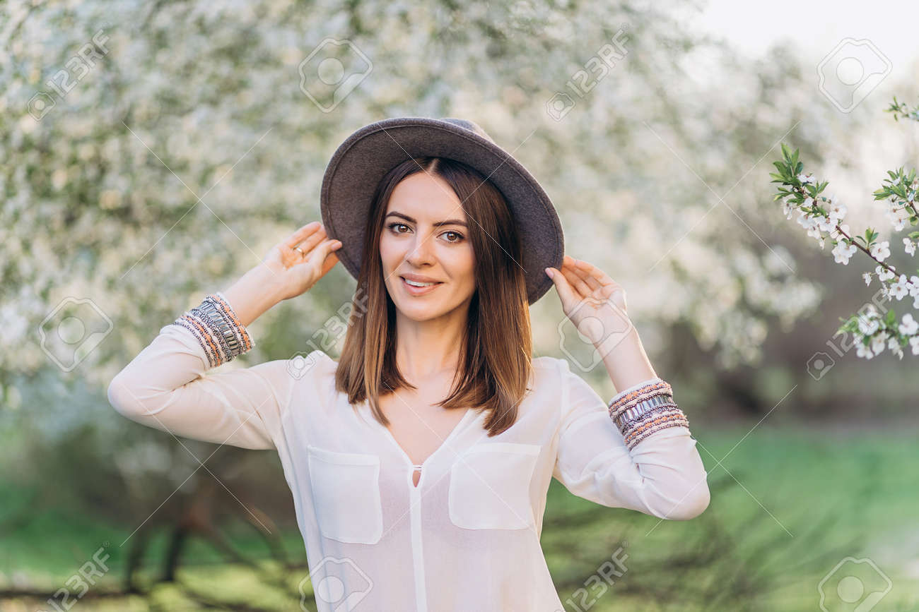 Amazing young woman in hat posing in Blooming tree orchard at spring - 148855194 Amazing young woman in hat posing in Blooming tree orchard at spring - 148855194