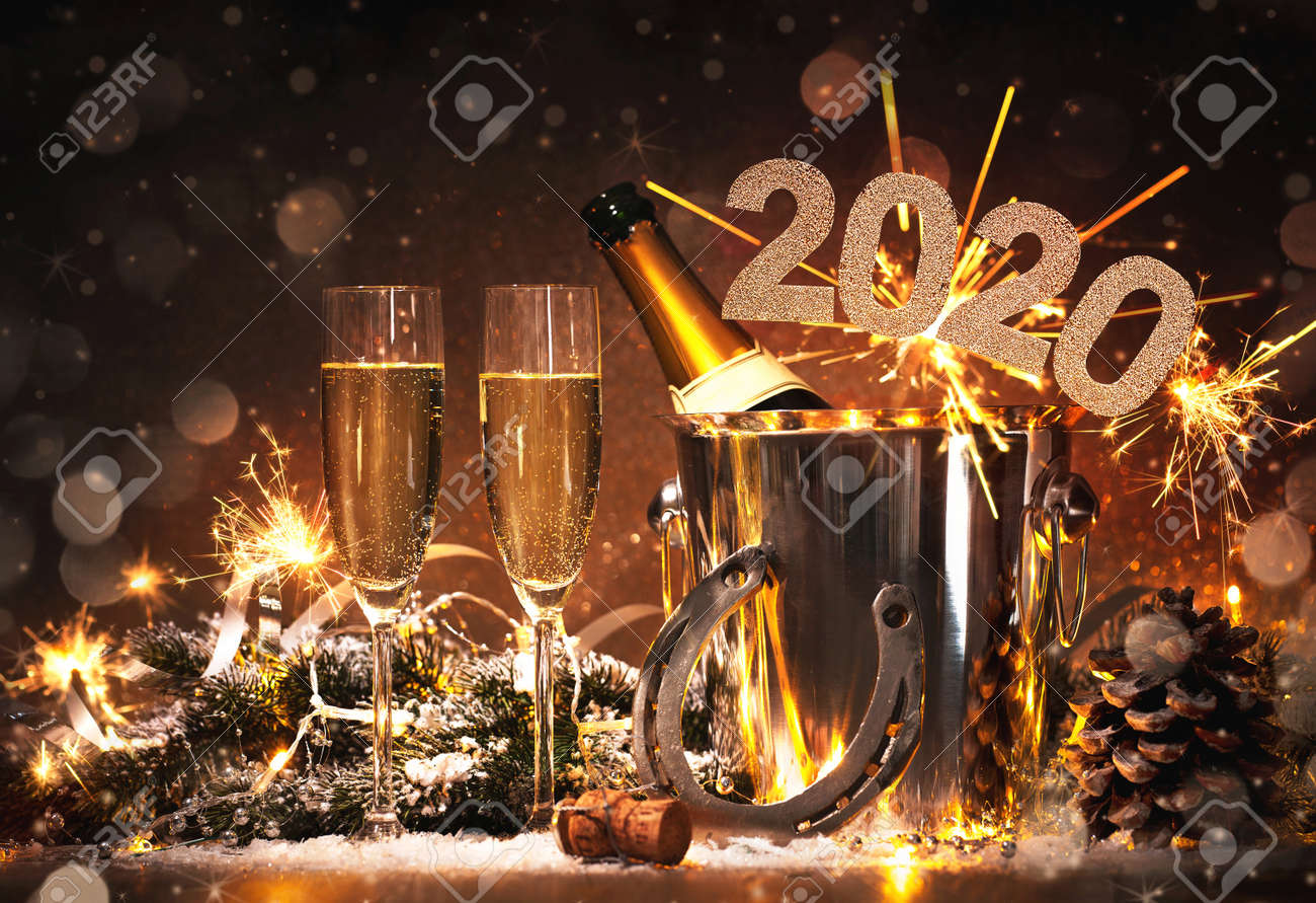 New Years Eve celebration background with pair of flutes and bottle of champagne in bucket and a horseshoe as lucky charm - 128483743 New Years Eve celebration background with pair of flutes and bottle of champagne in bucket and a horseshoe as lucky charm - 128483743