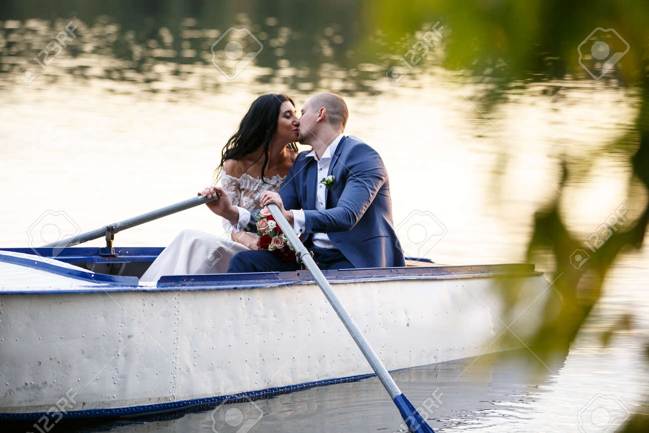 プレジャーボートで公園の池で結婚式のカップルの花嫁と新郎。 森の湖 