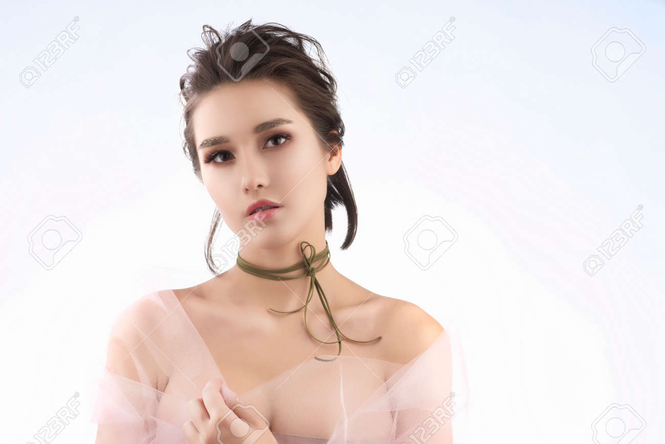 Beautiful Young Big Breast Asian Girl Wearing A Pink Veil On Her Naked  Shoulders And A Choker On Her Neck Sensually Puts Her Hands On Her Chest.  Isolated On White. Smooth Healthy