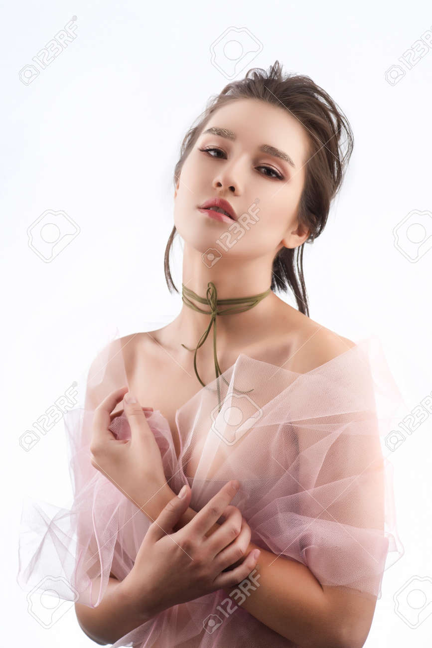 Beautiful Young Big Breast Asian Girl Wearing A Pink Veil On Her Naked  Shoulders And A Choker On Her Neck Sensually Puts Her Hands On Her Chest.  Isolated On White. Smooth Healthy