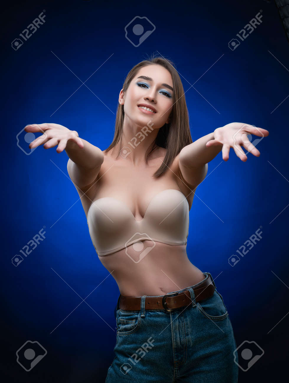 Beautiful Mixed Race Asian Girl With Big Breasts, Wearing A Bra And Jeans,  Smiles And Holds Out Her Hands Forward. Advertising, Commercial Design  Stock Photo, Picture and Royalty Free Image. Image 134595364.