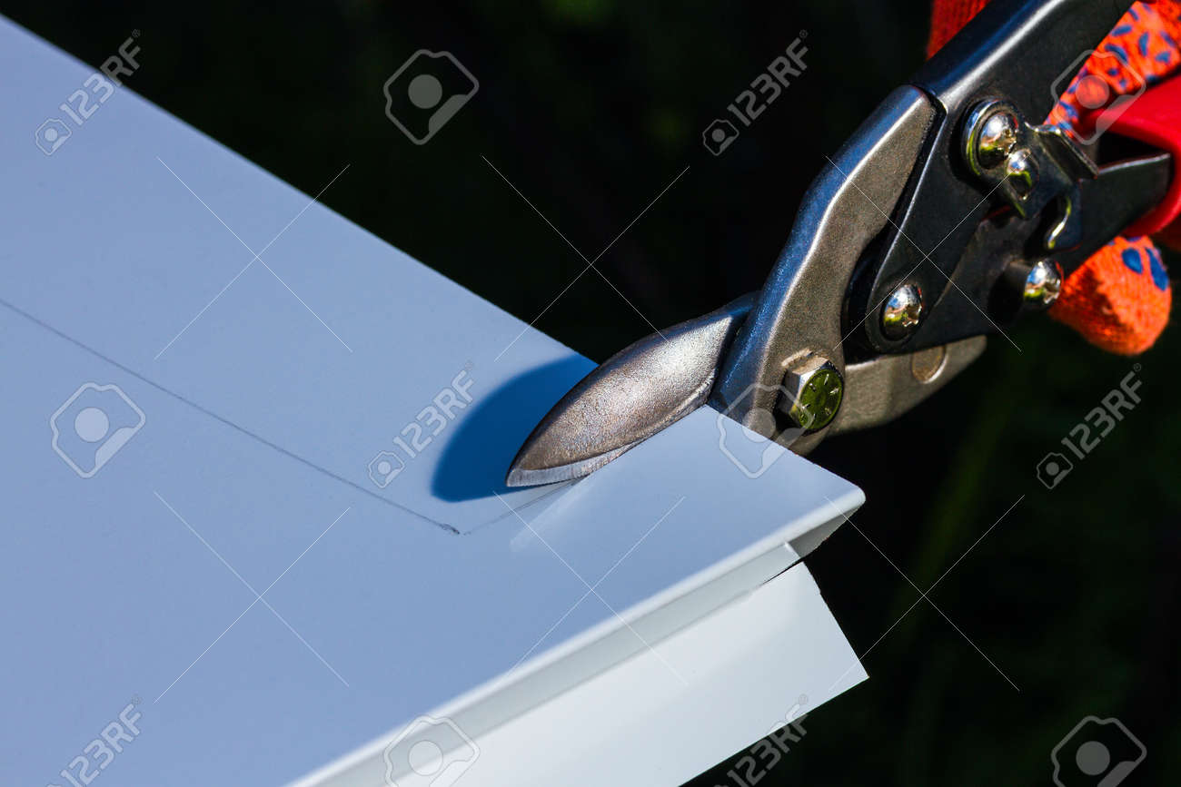 ビルダーは 頑丈なはさみを持つ金属のカッティング シートを手します の写真素材 画像素材 Image