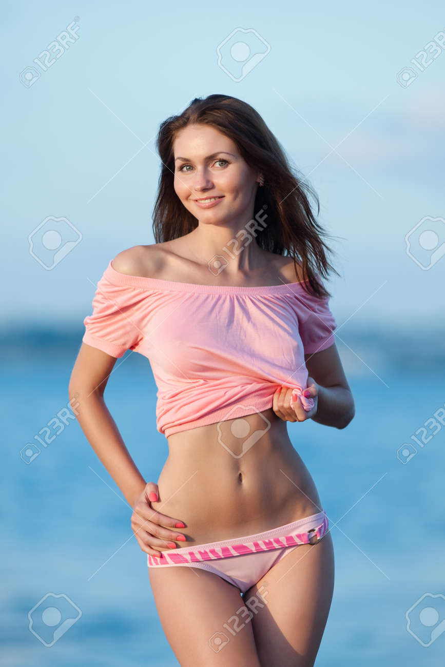 海の女の子 魅力的な若い女性が彼女のセクシーなおなか海の背景で表示します ピンクのブラウスとピンクのスイミング トランクス女性は戸外に脱いでいます の写真素材 画像素材 Image