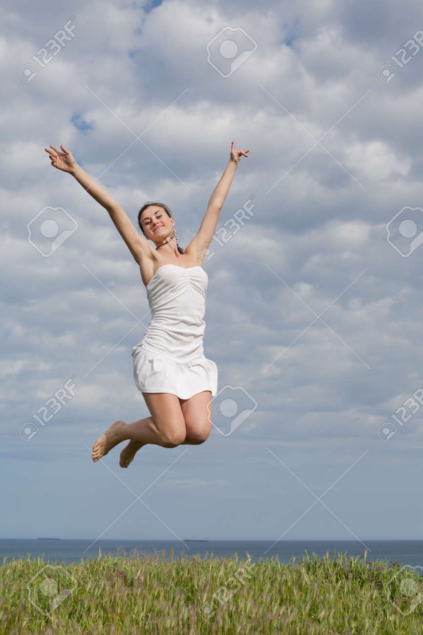 ジャンプの空の背景に白いドレスにオープンエア魅力的な若い女性にホワイトの女の子 の写真素材 画像素材 Image
