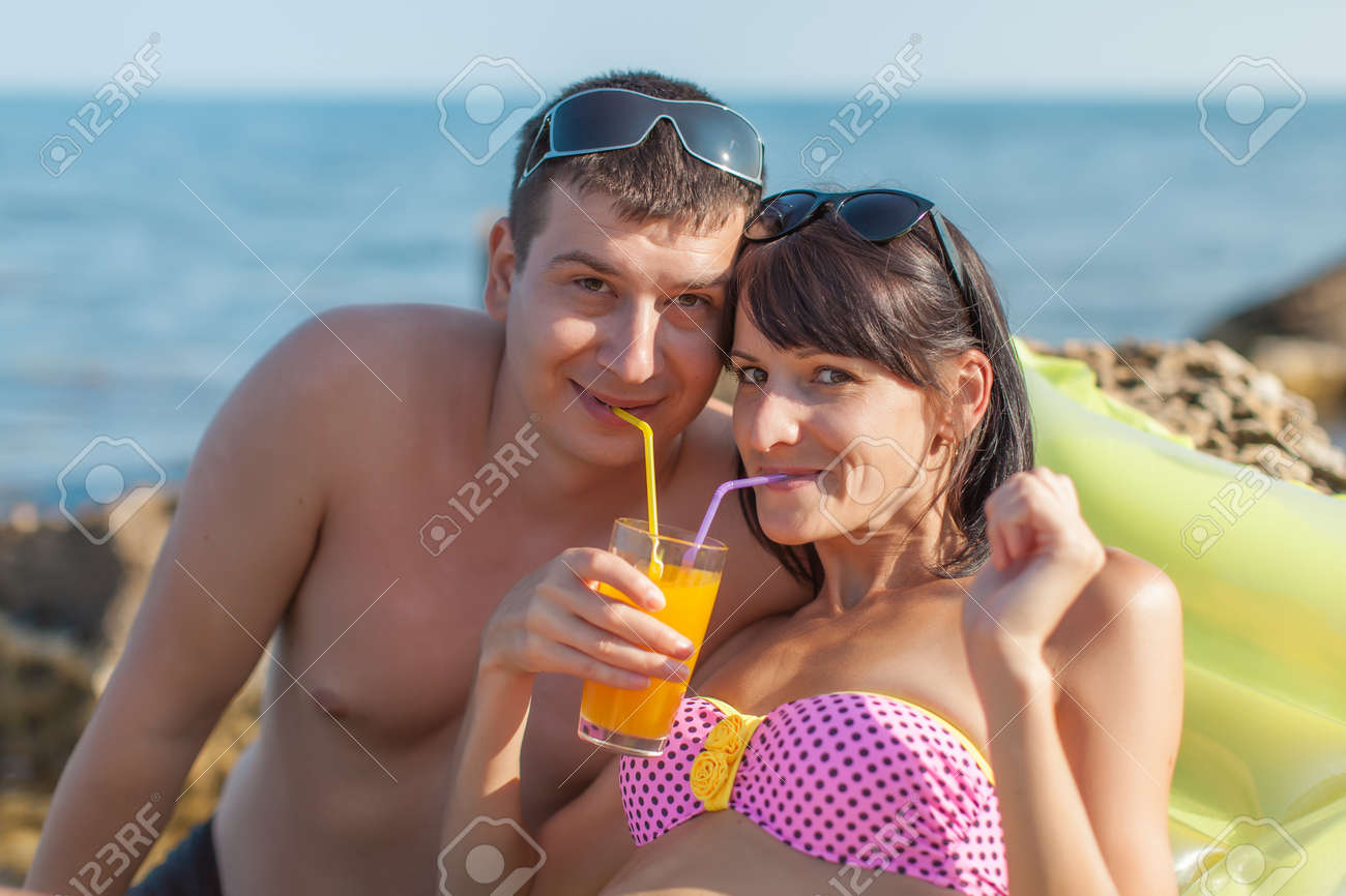 海で幸せなカップル 若い男と女が 1 つのガラスからストローでジュースを飲む の写真素材 画像素材 Image