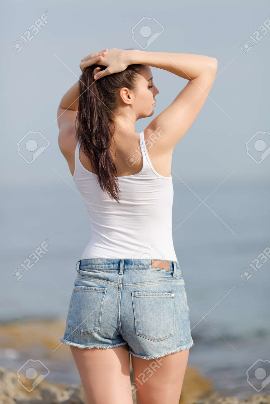 海で女の子 白いタンクトップの魅力的な若い女性は彼女の髪型 リアビューを調整します の写真素材 画像素材 Image 海で女の子 白いタンクトップの魅力的な若い女性は彼女の髪型 リアビューを調整します の写真素材 画像素材 Image