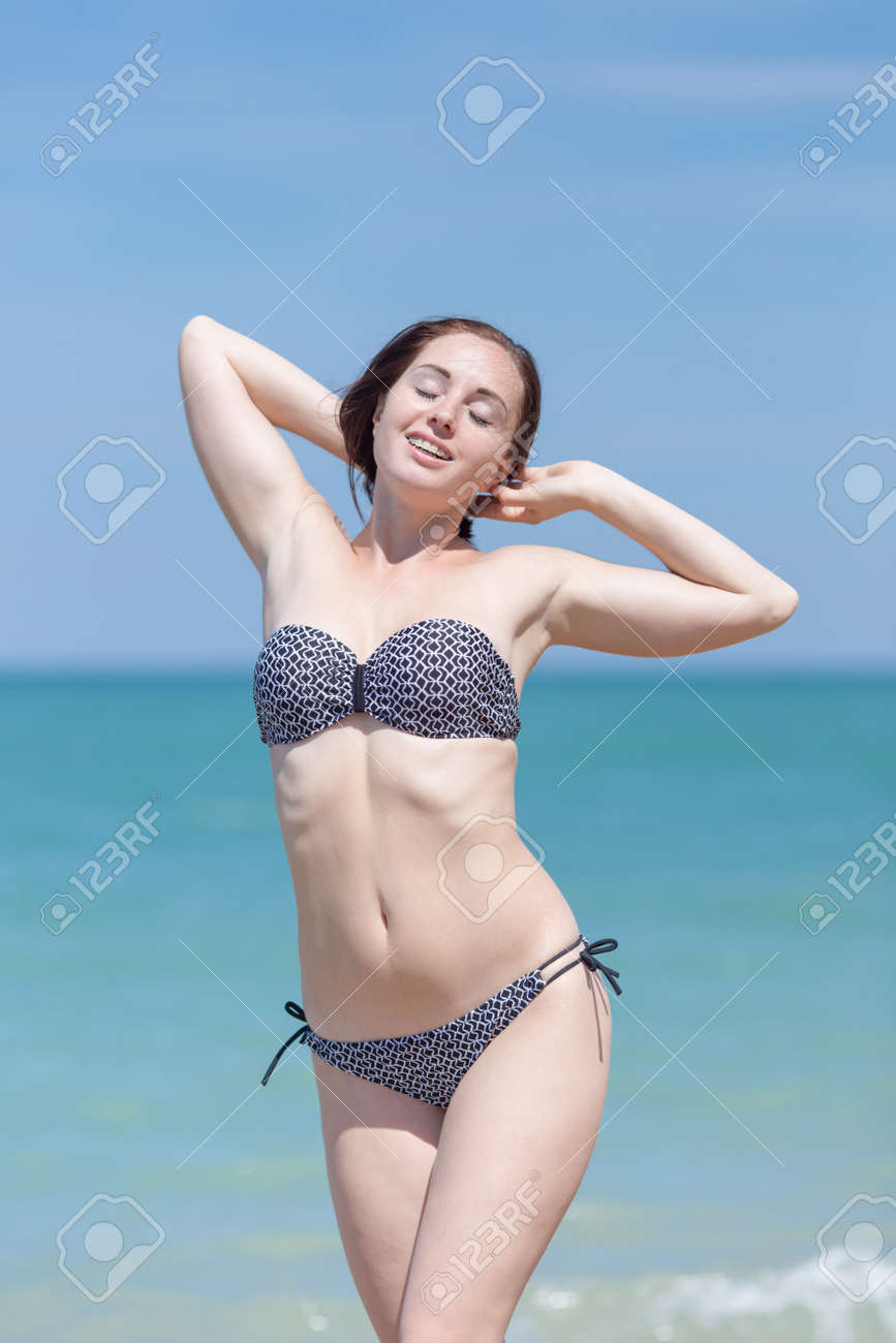 海で水着を着た女の子 目を閉じて 頭の後ろに手を置いてポーズをとる水着の女性 の写真素材 画像素材 Image