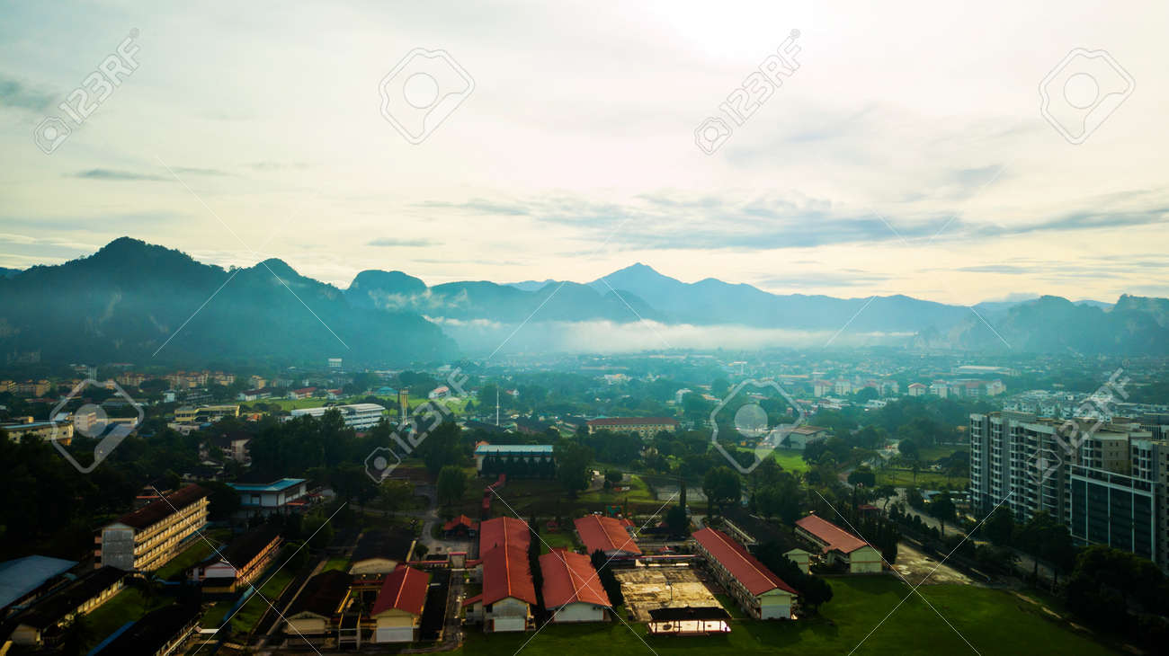 Aerial photography of a mist covered mountain in Ipoh during sunrise with a school in the foreground. - 123744422 Aerial photography of a mist covered mountain in Ipoh during sunrise with a school in the foreground. - 123744422