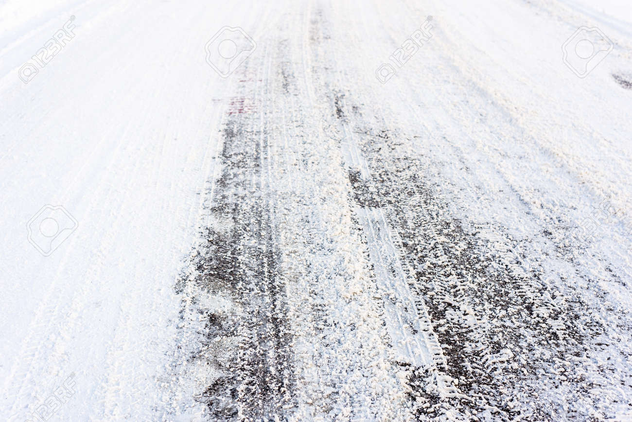 country road in winter asphalt covered snow with tire tracks