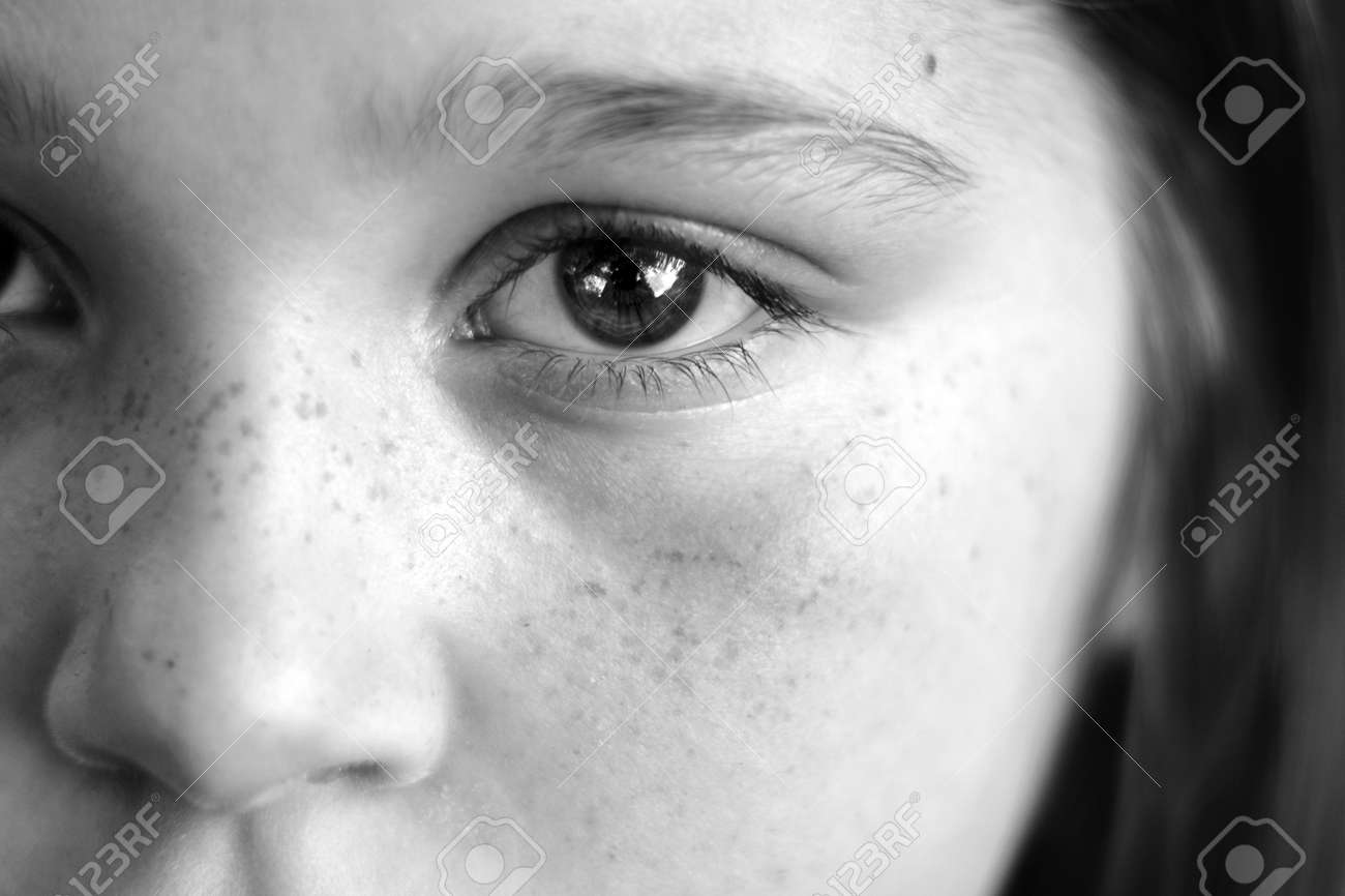 Black and white closeup of a girls face with expressive eyes reflections in eye