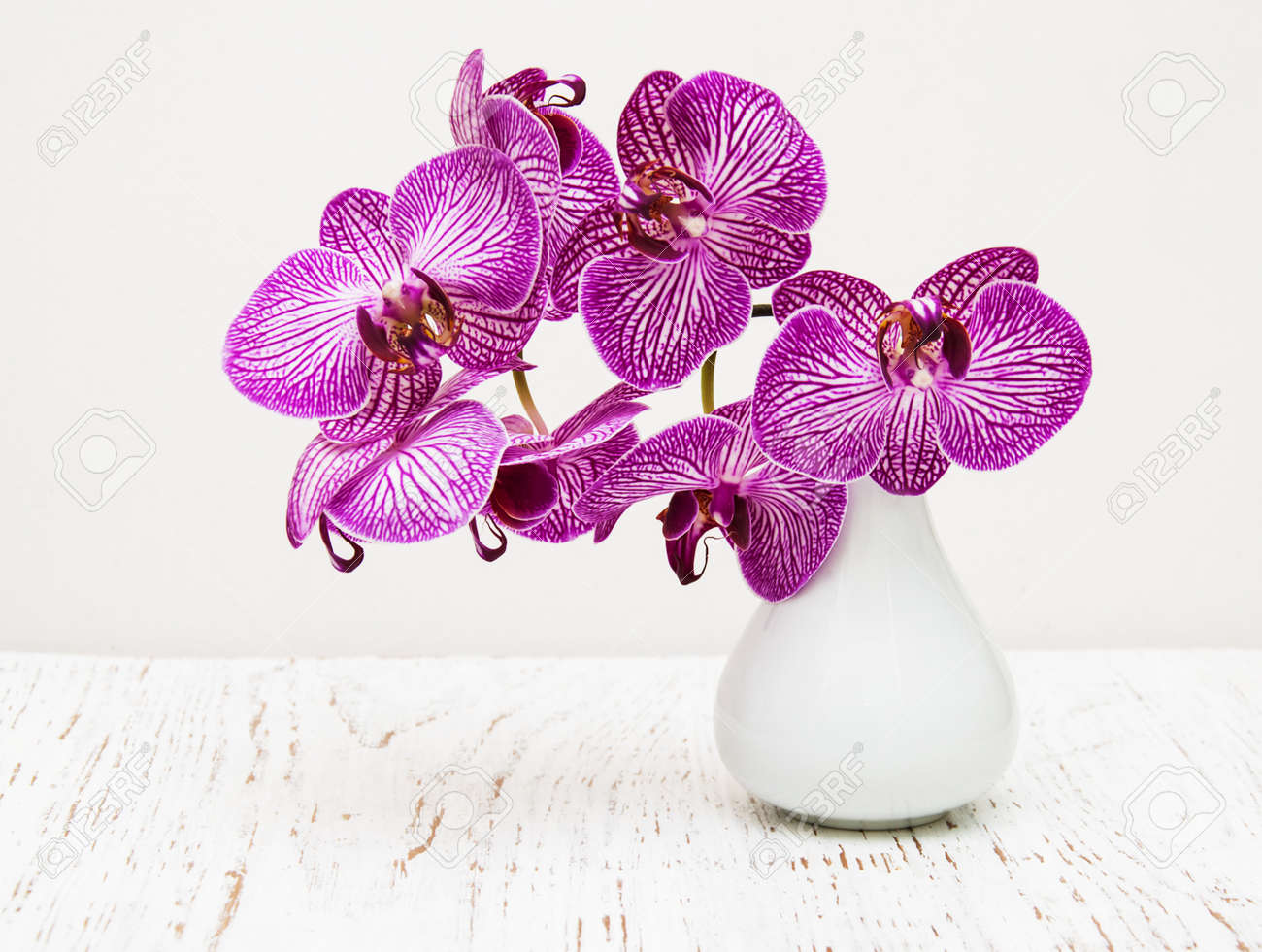 Purple Orchid Flowers In Vase On A Wooden Table Stock Photo