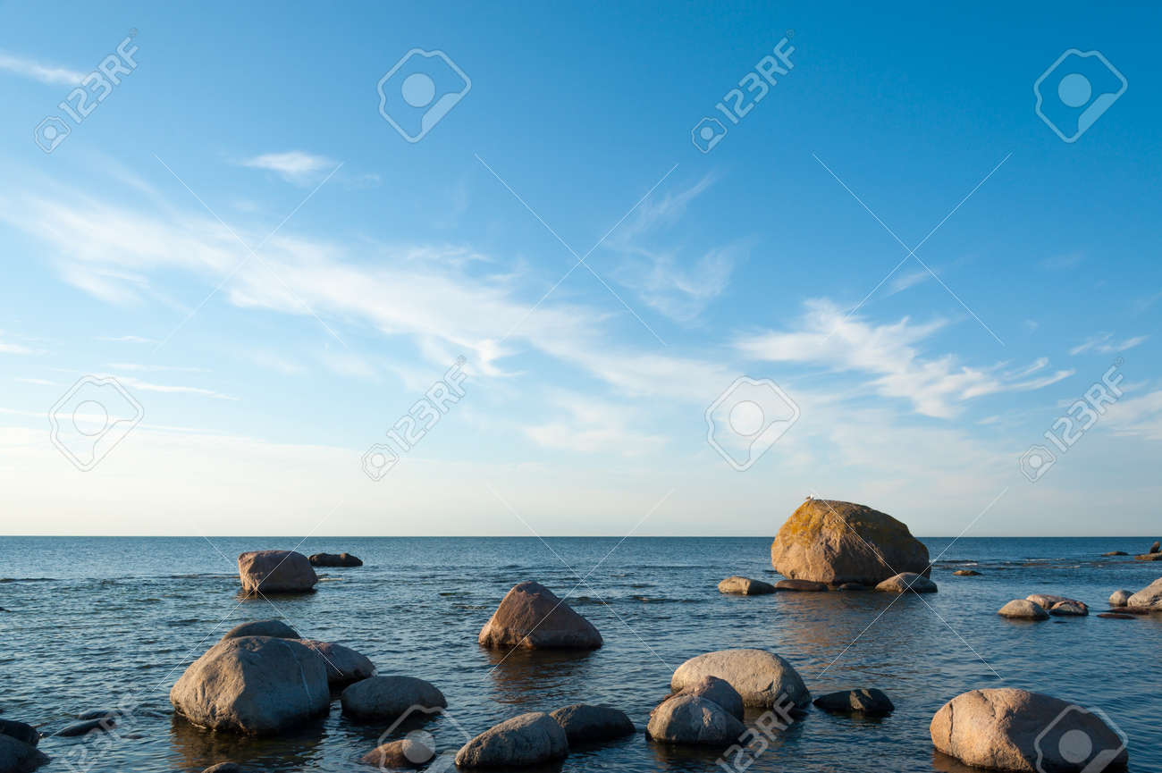 Low Angle View Of A Rocky Ocean Coastal Background With Calm Blue ...