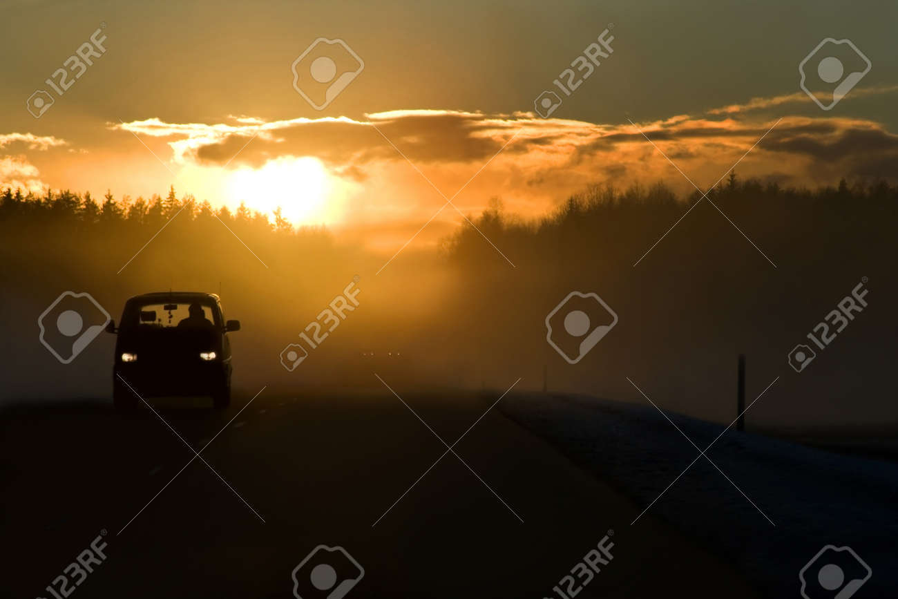 Fog on the road at the start of winter. Bright sun in clouds, minivan on the left side of road and dangerous overtaking in the background. This is E22/A10 winter road Riga - Ventspils. - 9828429 Fog on the road at the start of winter. Bright sun in clouds, minivan on the left side of road and dangerous overtaking in the background. This is E22/A10 winter road Riga - Ventspils. - 9828429