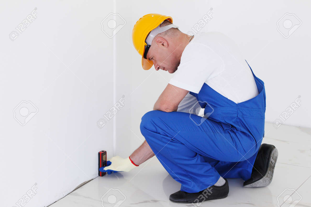 the worker makes finishing works of walls using laser line level finishing works in construction