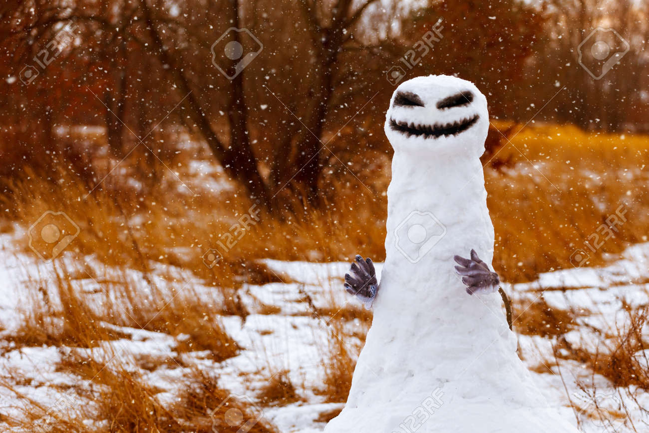 scary snowman as a monster on a background of yellow grass