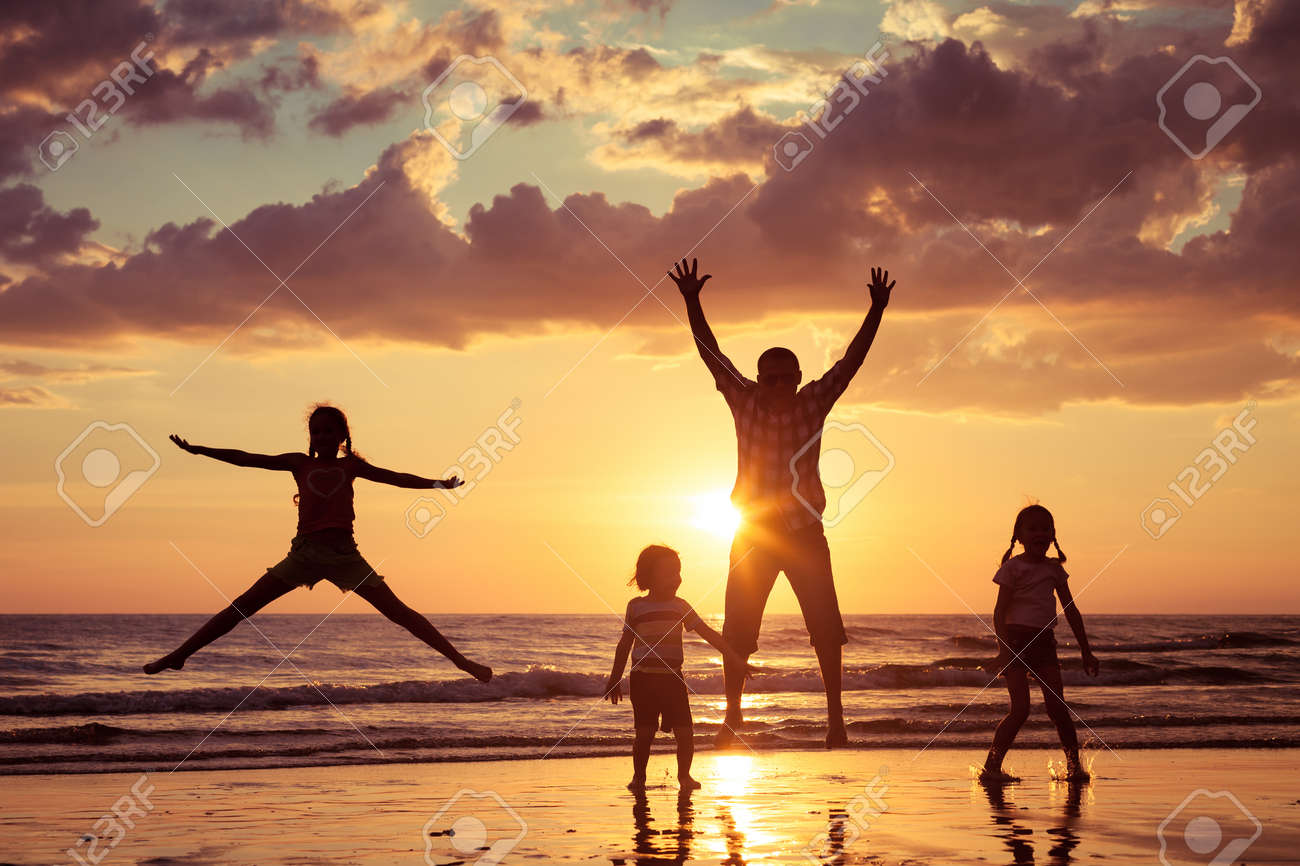 Father and children playing on the beach at the sunset time. Concept of friendly family. - 46432387 Father and children playing on the beach at the sunset time. Concept of friendly family. - 46432387