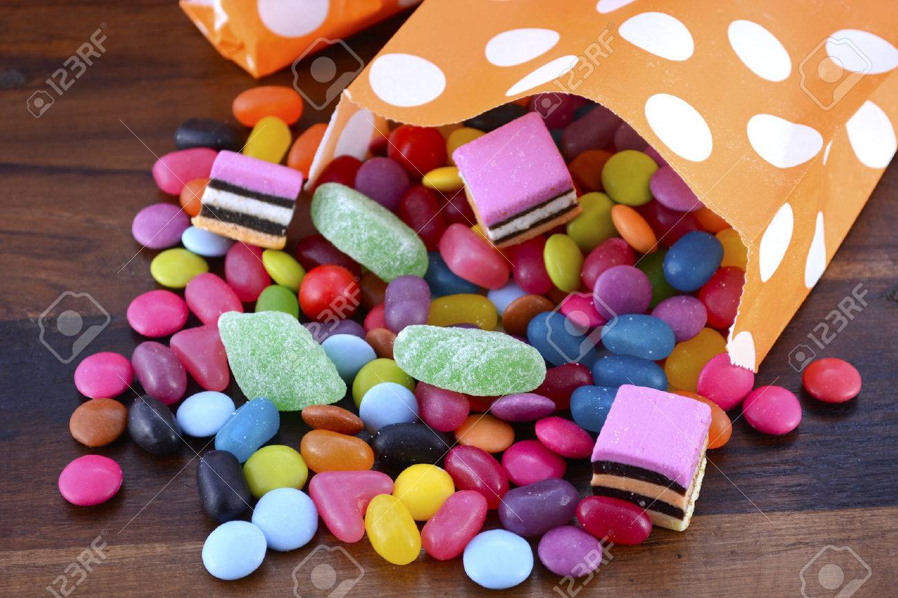 Halloween Party Trick of Treat Candy with candy flowing from orange polka dot party favor bag on dark wood background. - 46091687 Halloween Party Trick of Treat Candy with candy flowing from orange polka dot party favor bag on dark wood background. - 46091687