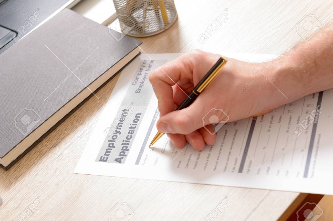 filling in blank employment application form in hands on a desk