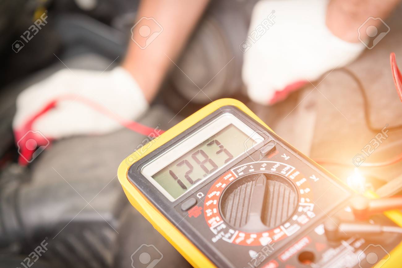 Car mechanic uses a multimeter to check car battery voltage - 82272829 Car mechanic uses a multimeter to check car battery voltage - 82272829
