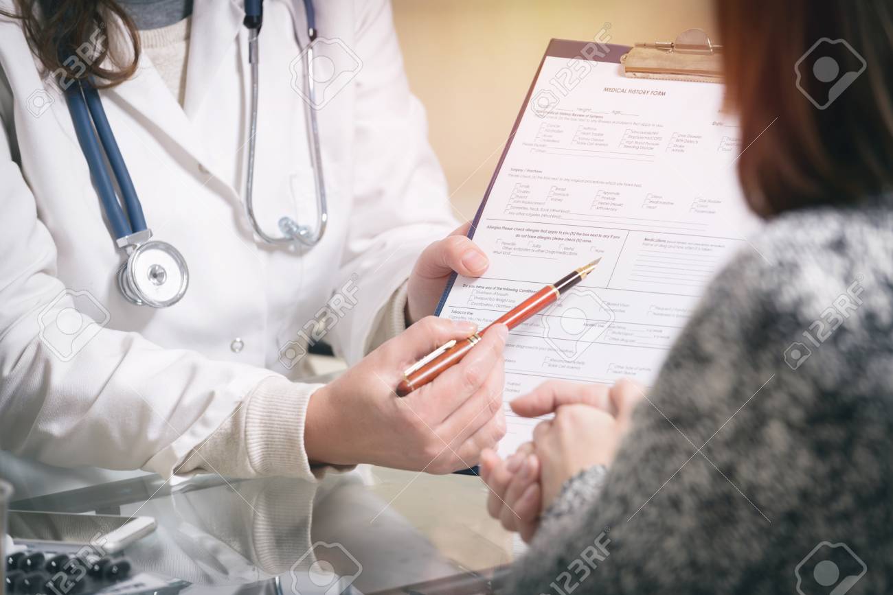 Medical doctor presenting medical history form to her patient - 91328202 Medical doctor presenting medical history form to her patient - 91328202