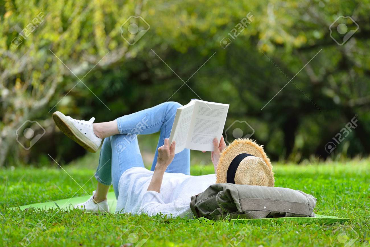 Happy woman lying on green grass reading a book in the park( outdoors ) - 68788846 Happy woman lying on green grass reading a book in the park( outdoors ) - 68788846