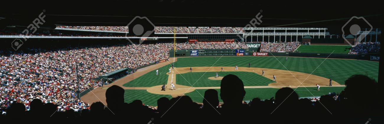 これは 球場で遊ばれるメジャー リーグ野球ゲームです チームは テキサス レンジャー対ボルティモア オリオールズです 大群衆とスタンドに前景はシルエットで座ってのファンがあります の写真素材 画像素材 Image