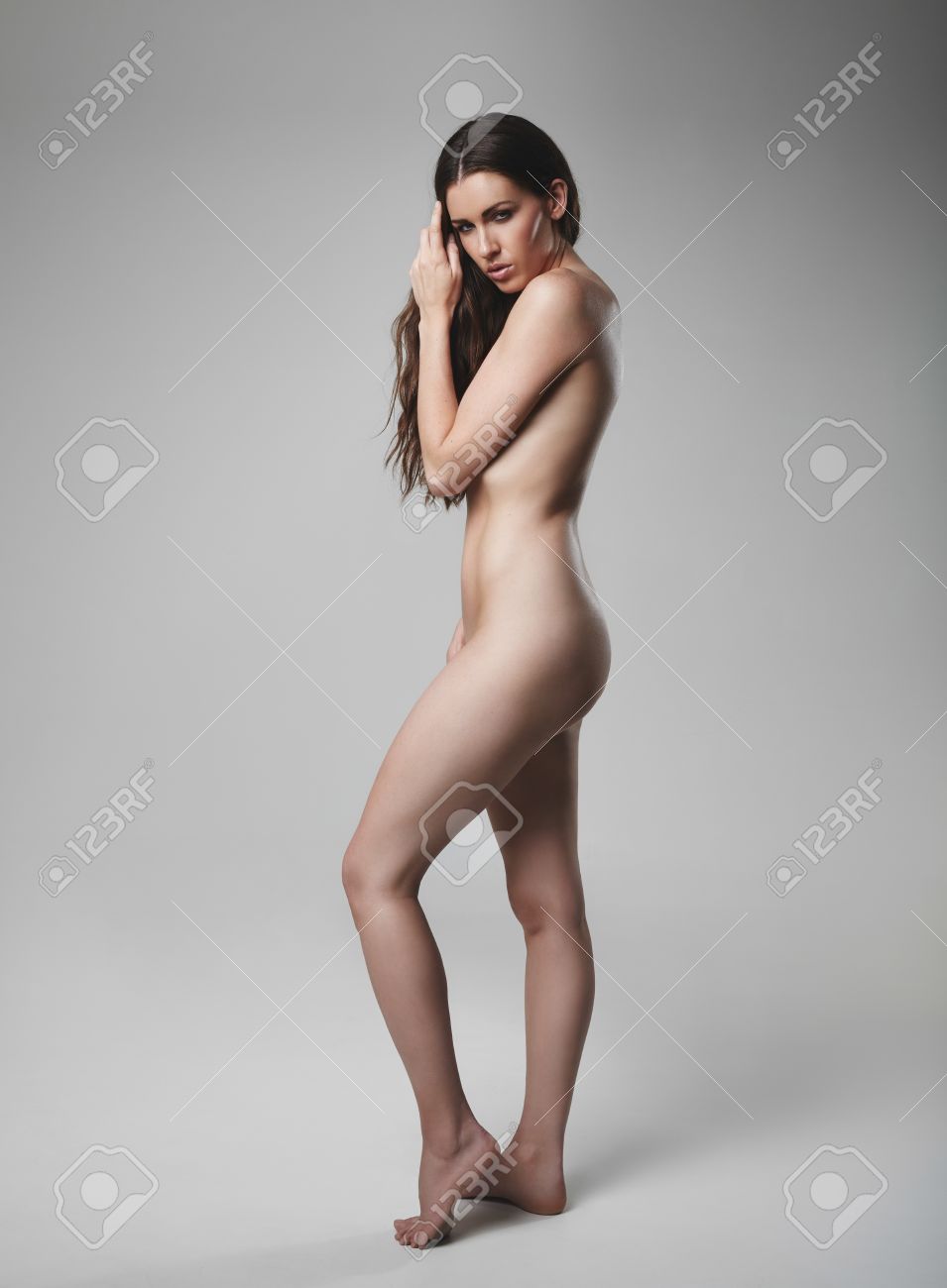カメラを見て裸の若い女性の完全な長さの肖像画 白人女性のモデルは灰色の背景上のヌードのポーズします の写真素材 画像素材 Image