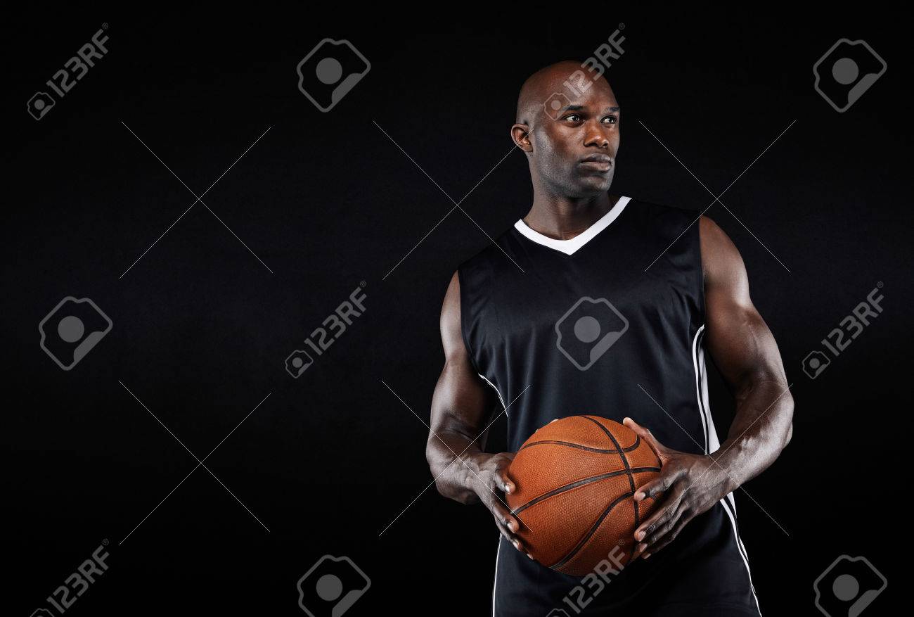 Copyspace とよそ見バスケット ボールを保持しているフィット若いアフロ アメリカ選手の画像です 黒い背景に筋肉のバスケット ボール選手 の写真素材 画像素材 Image