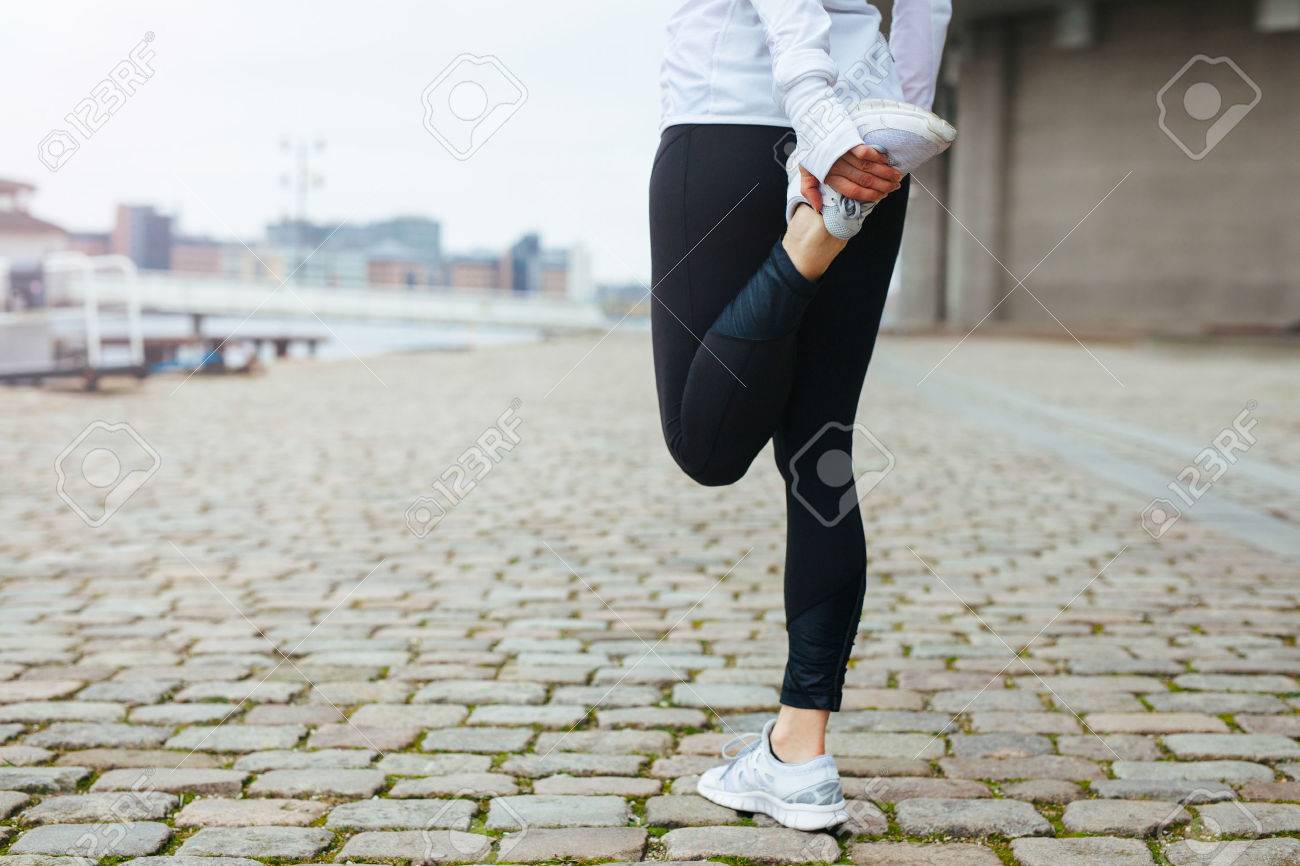 Low section view of fit young woman stretching her leg before a run in city streets. Preparation for running workout. - 35751743 Low section view of fit young woman stretching her leg before a run in city streets. Preparation for running workout. - 35751743