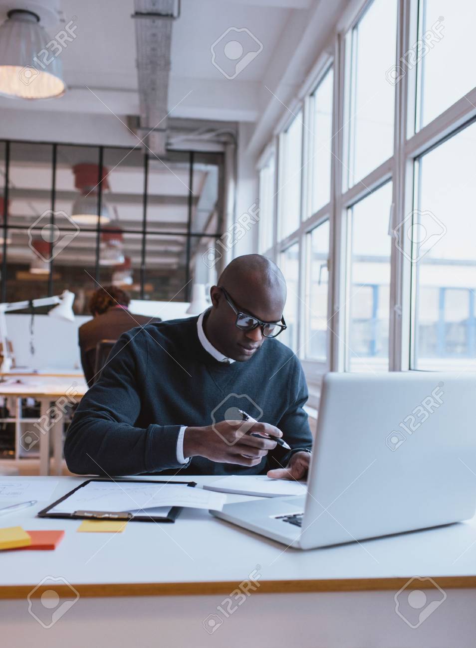 若いアフリカの実業家は彼の机で作業しながらメモを取るします エグゼクティブ オフィスで働きます の写真素材 画像素材 Image