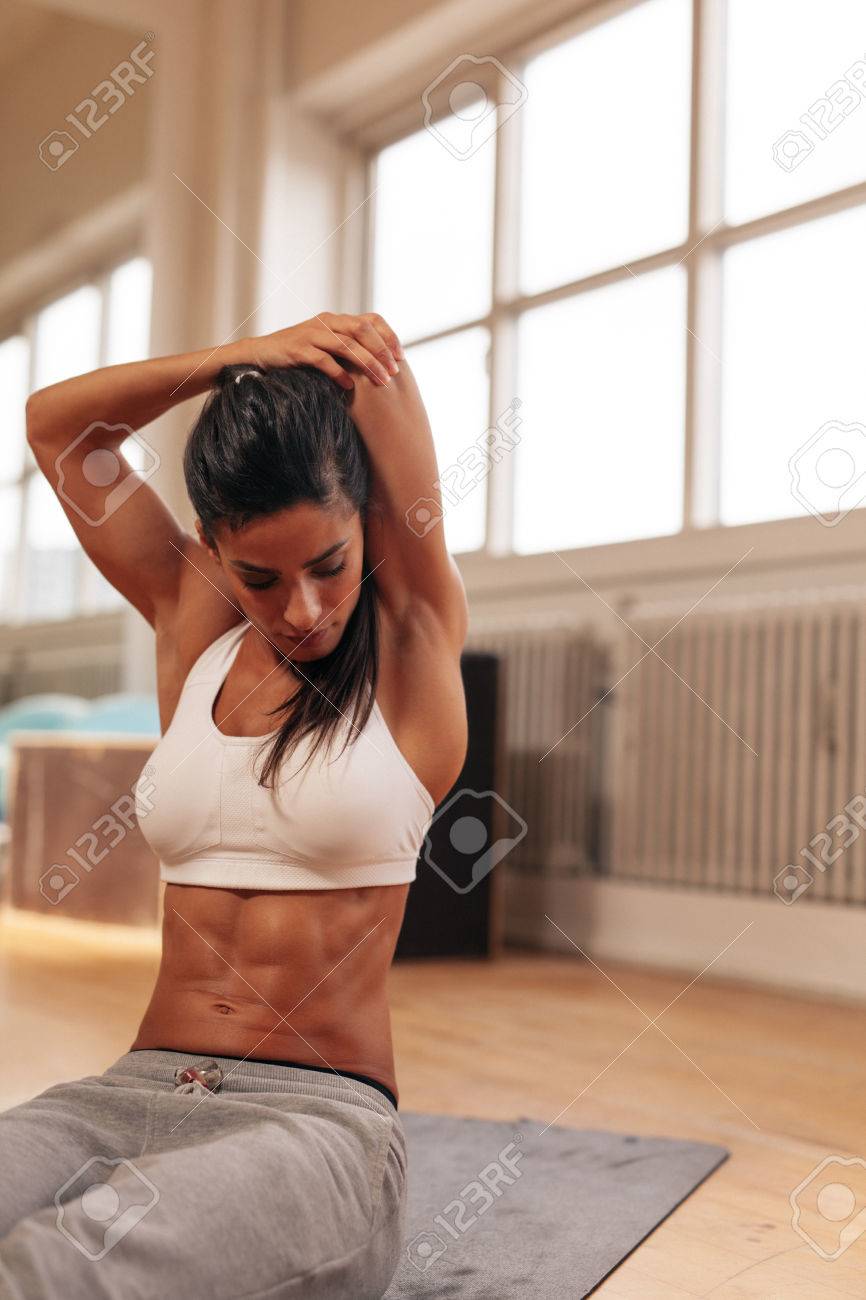 ジムで彼女の背中の後ろに腕を伸ばす筋肉の若い女性 の写真素材 画像素材 Image