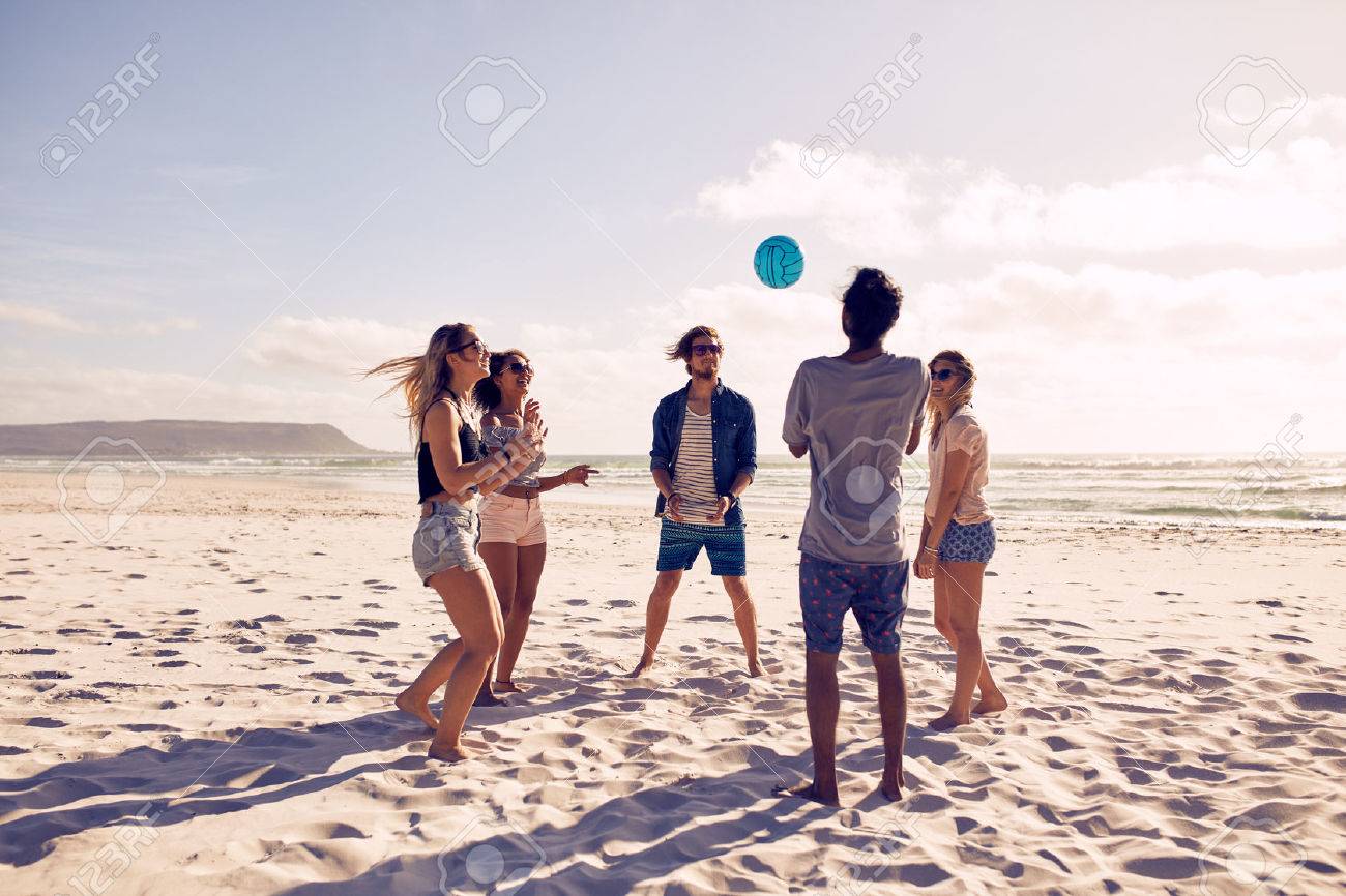 Group of young people playing with ball at the beach. Young friends enjoying summer holidays on a sandy beach. - 51998828 Group of young people playing with ball at the beach. Young friends enjoying summer holidays on a sandy beach. - 51998828