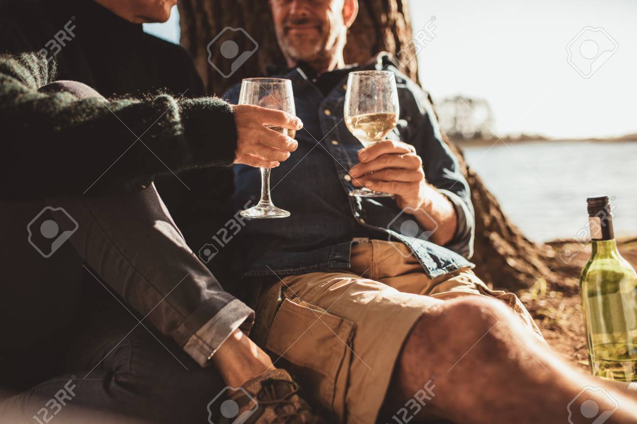ワインのガラスと一緒に座っている愛情のある成熟したカップルの画像をトリミングしました 男と女のキャンプや ワインのガラスを保持しています の写真素材 画像素材 Image