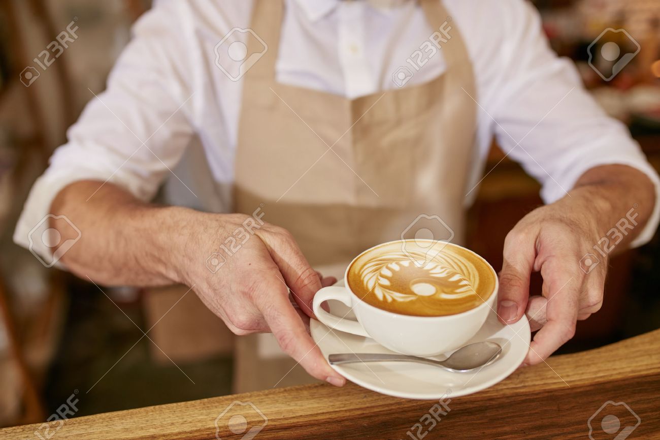 Closeup Of Man In Apron Serving Coffee While Standing In Coffee - Closeup Of Man In Apron Serving Coffee While Standing In Coffee Shopbarista closeup of man in apron serving coffee while standing in coffee - closeup of man in apron serving coffee while standing in coffee shopbarista