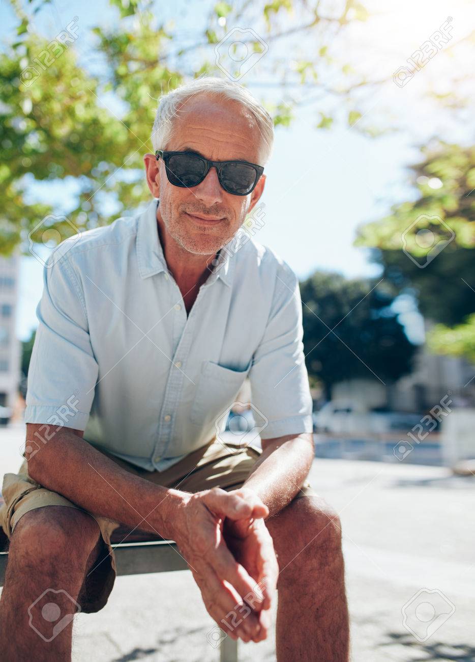 Retrato De Hombre Maduro Hermoso Que Se Sienta Al Aire Libre. Turista Varón Mayor Con Gafas Sol Sentado Fuera La Ciudad En Un Día De Verano. Fotos, Imágenes Y