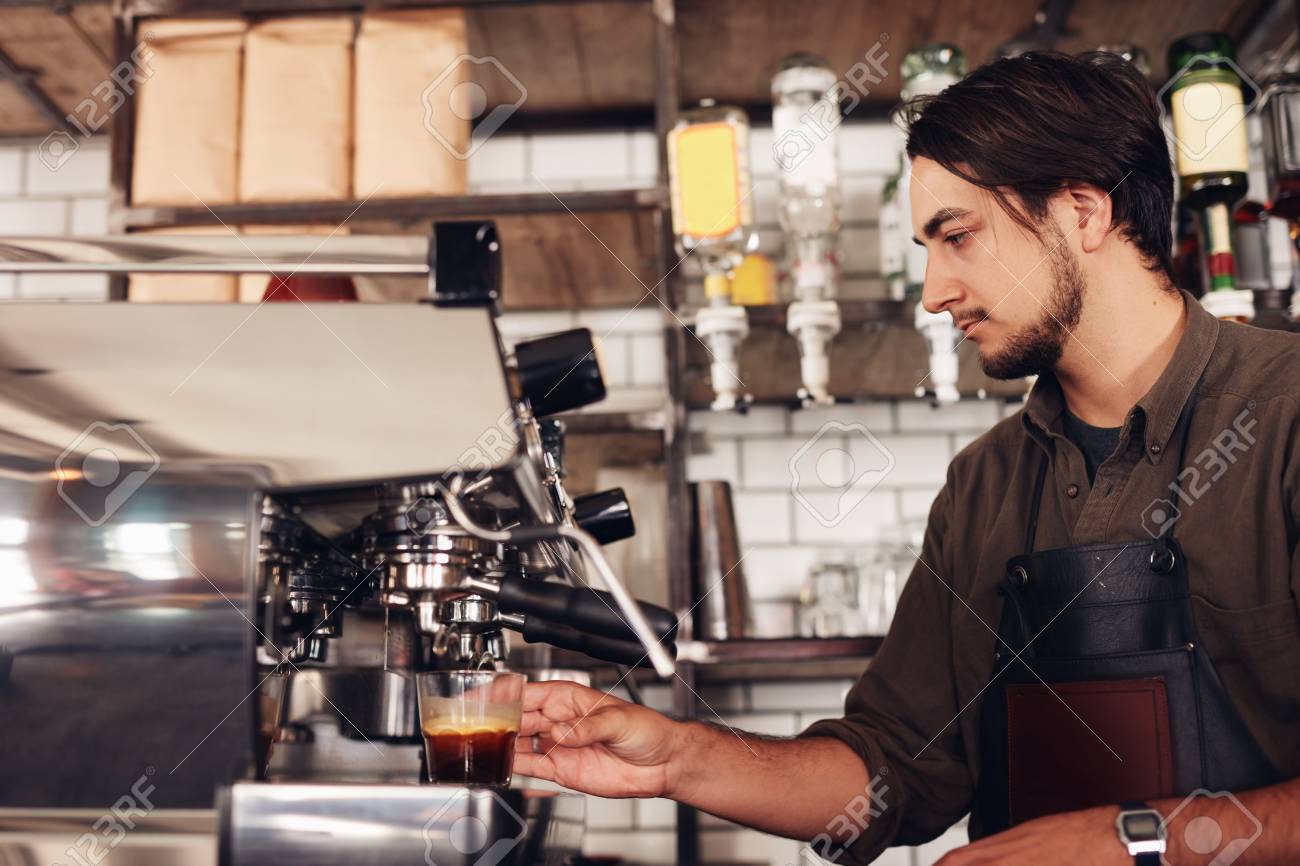 Side View Of Male Barista Preparing Espresso At Coffee Shop Young Man In Apron Making Side View Of Male Barista Preparing Espresso At Coffee Shop Young Man In Apron Making