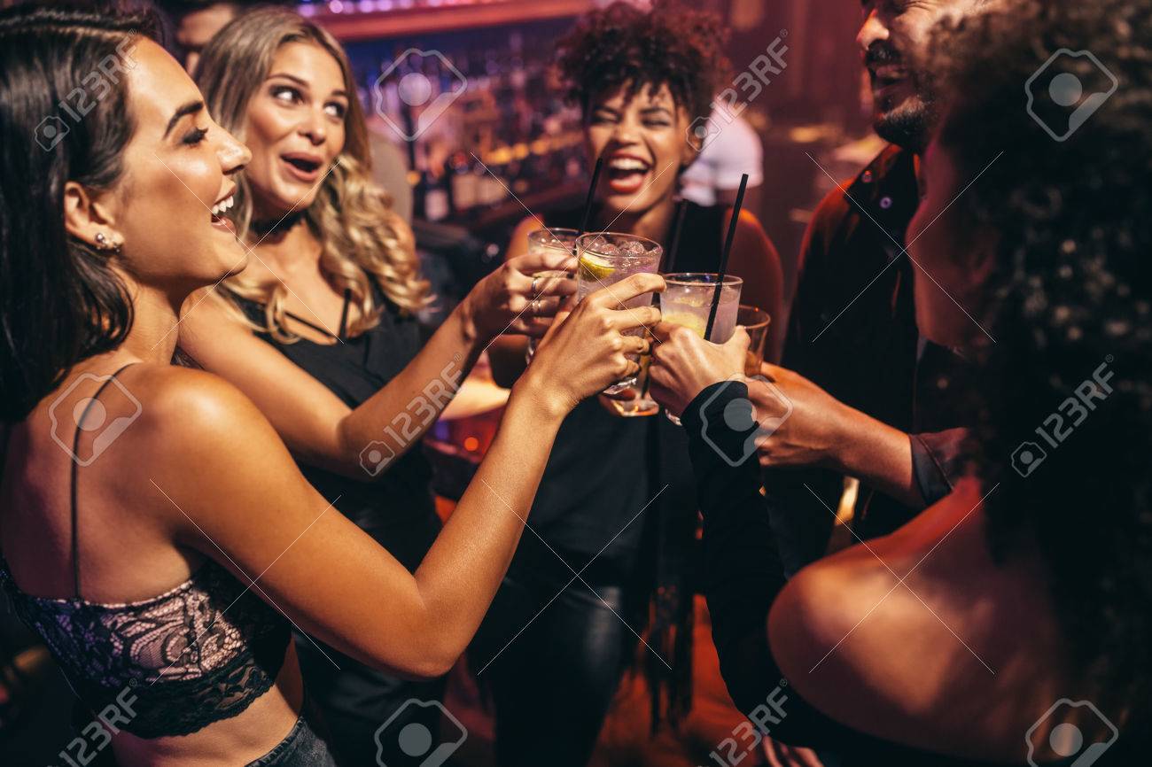 group of friends partying in a nightclub and toasting drinks