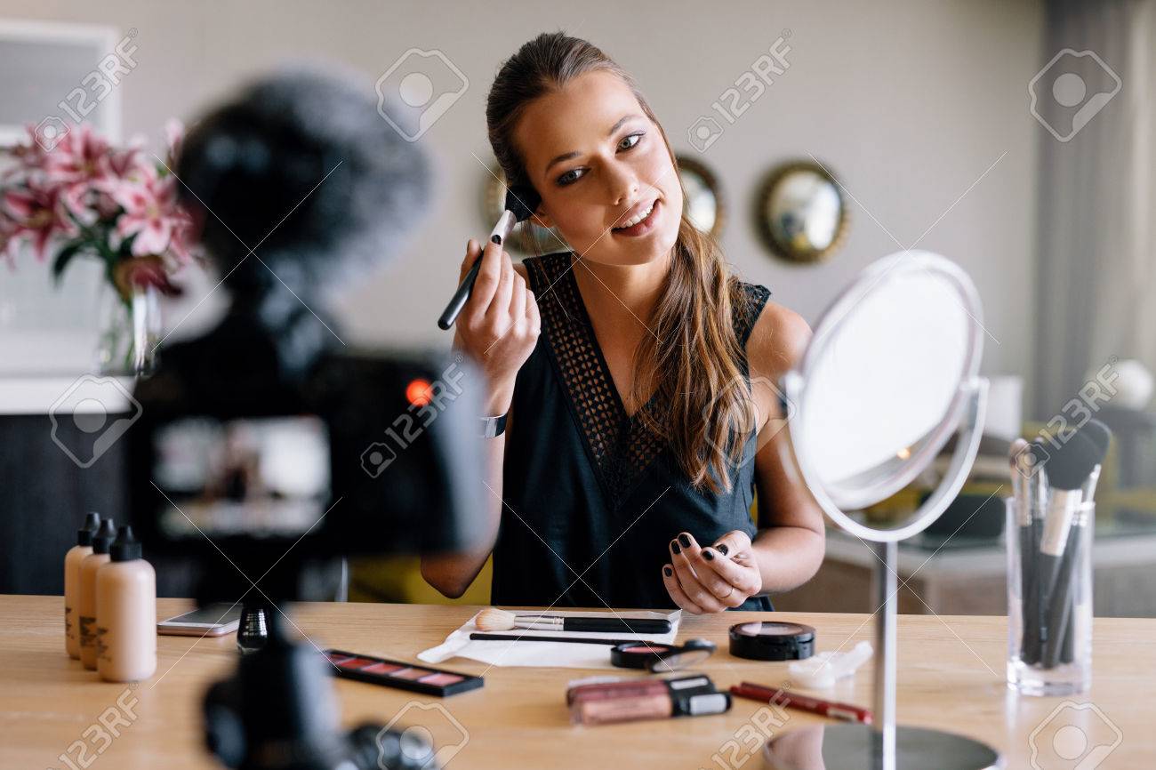 Young lady recording her video while applying cosmetics. Woman making a video for her blog on cosmetics. - 74642568 Young lady recording her video while applying cosmetics. Woman making a video for her blog on cosmetics. - 74642568