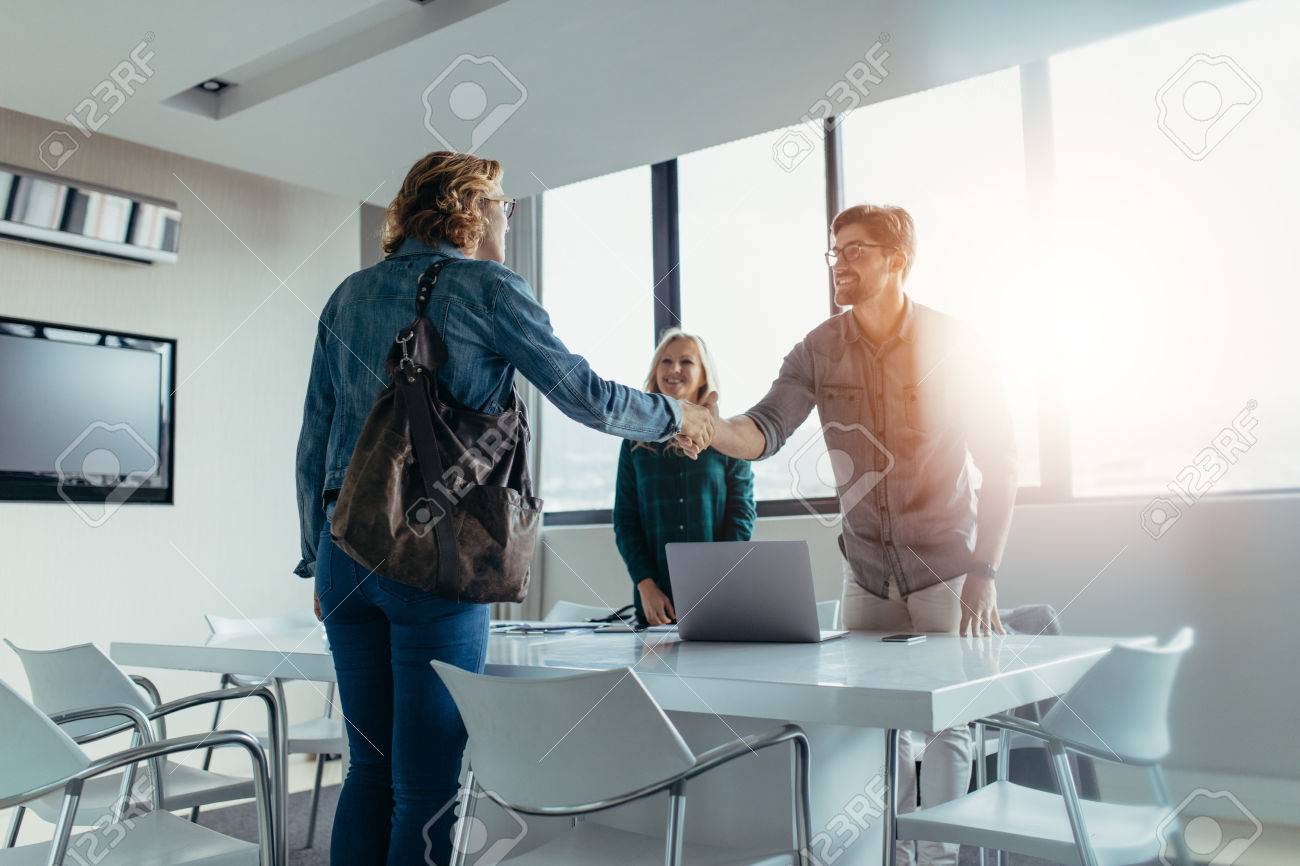 Business people finishing up a meeting. Man shaking hands with female client after successful deal. - 82510602 Business people finishing up a meeting. Man shaking hands with female client after successful deal. - 82510602