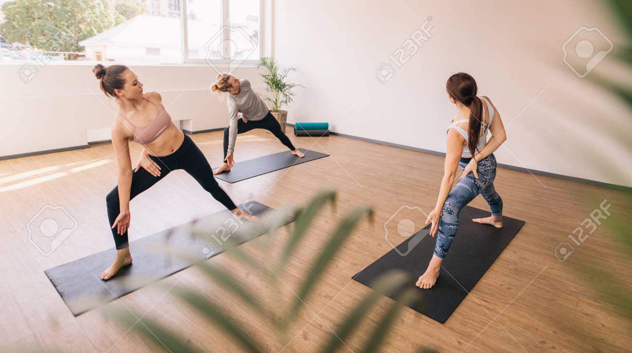 three people practising yoga in class group of people standing