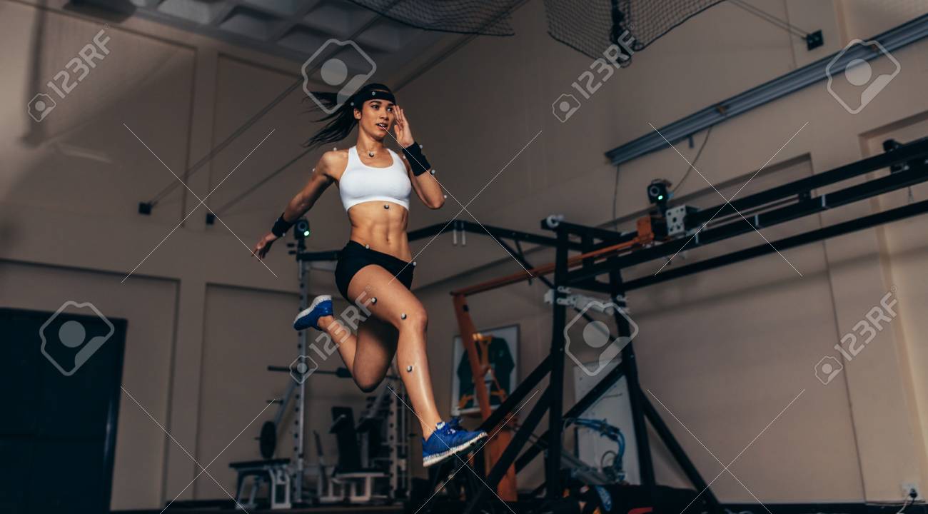 Female athlete with motion capture sensors on her body running in biomechanical lab. Recording the movement and performance of sportswoman in sports science lab. - 91084957 Female athlete with motion capture sensors on her body running in biomechanical lab. Recording the movement and performance of sportswoman in sports science lab. - 91084957