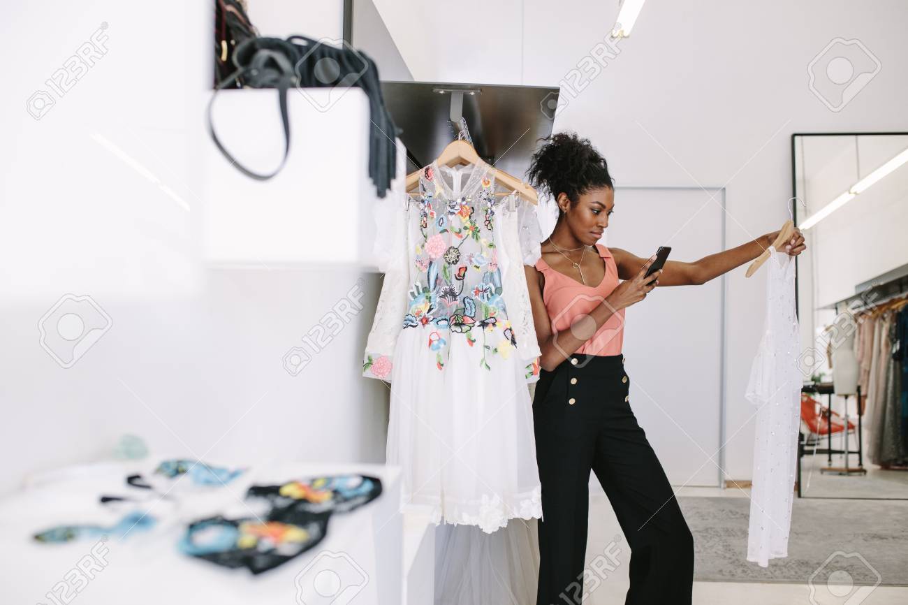 Fashion designer taking photograph of a designer dresses in her..