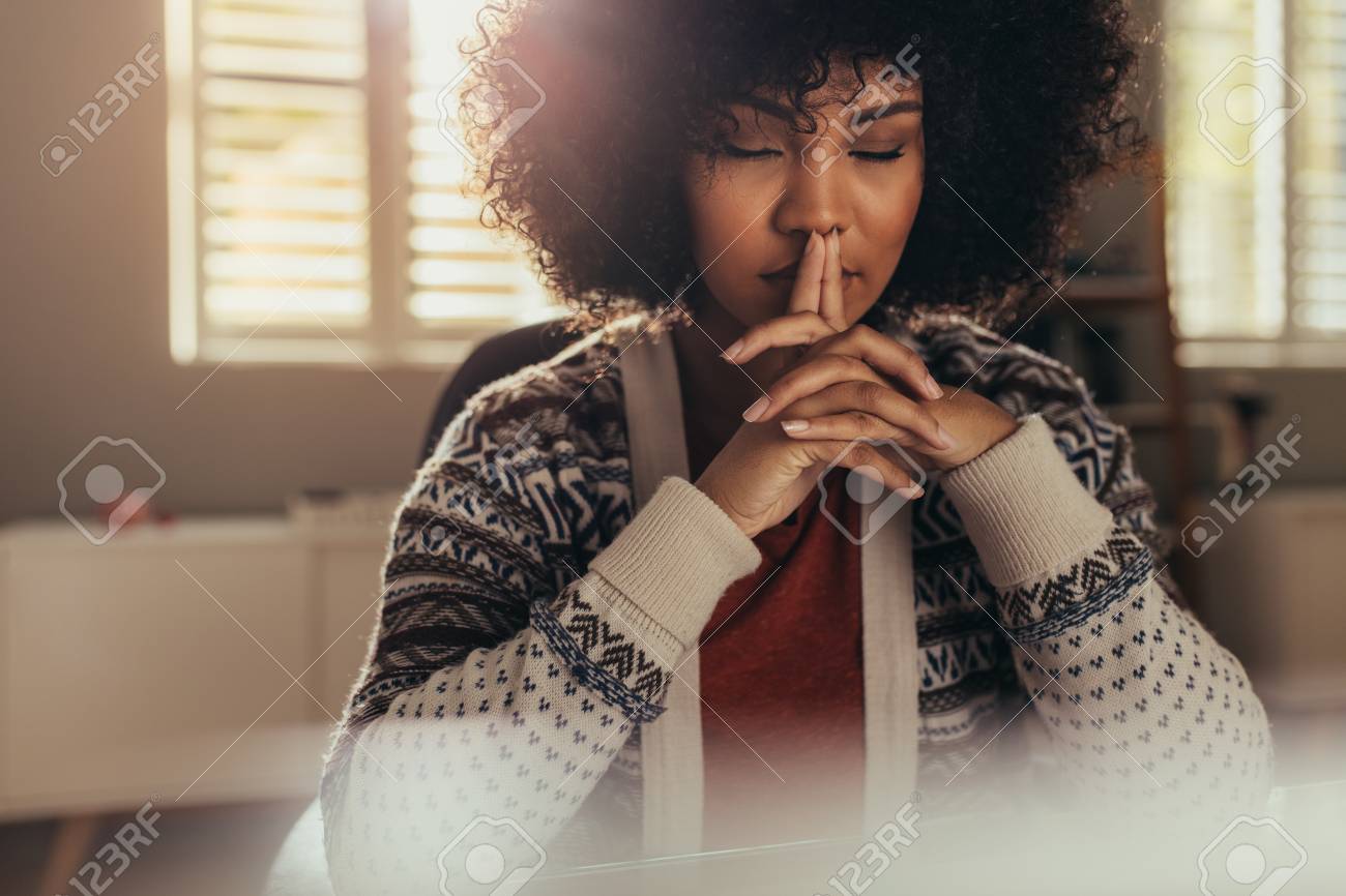 African female sitting at her work desk and thinking with her eyes closed. Stressed woman taking a break to come up with solution using mindfulness. - 111942745 African female sitting at her work desk and thinking with her eyes closed. Stressed woman taking a break to come up with solution using mindfulness. - 111942745