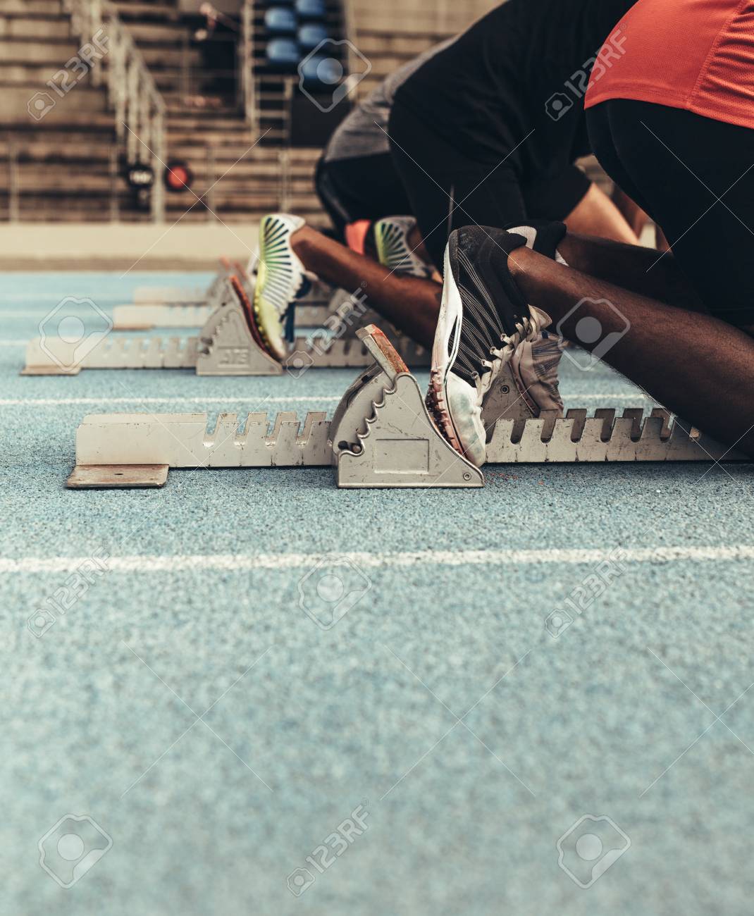 Sprinters on their mark ready to sprint on an all weather running track. Runners using a starting block to start their run on the race track. - 113593410 Sprinters on their mark ready to sprint on an all weather running track. Runners using a starting block to start their run on the race track. - 113593410