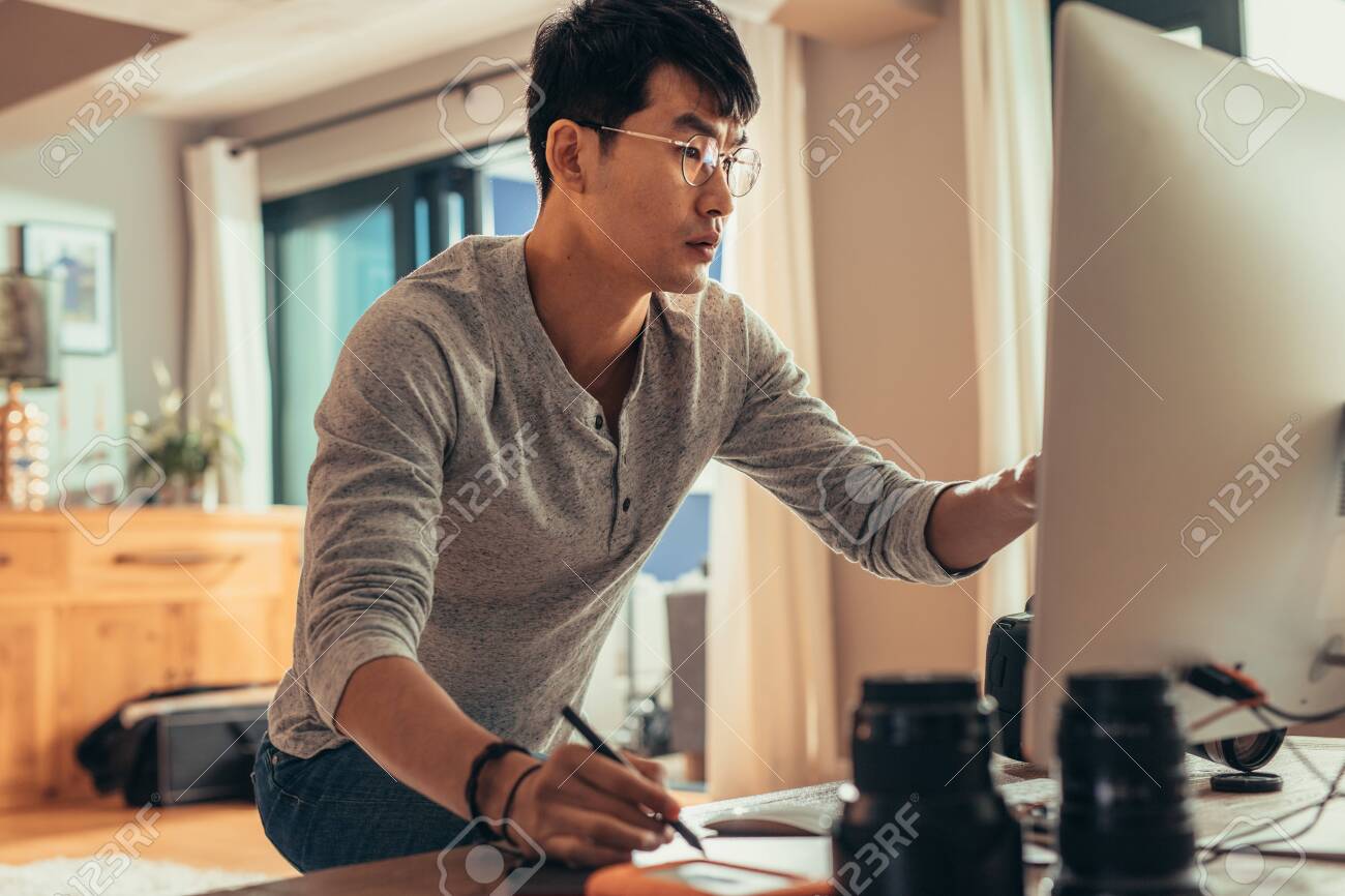 Photographer editing sample shoots on his computer in studio. Man working on computer in photo studio. - 116932385 Photographer editing sample shoots on his computer in studio. Man working on computer in photo studio. - 116932385