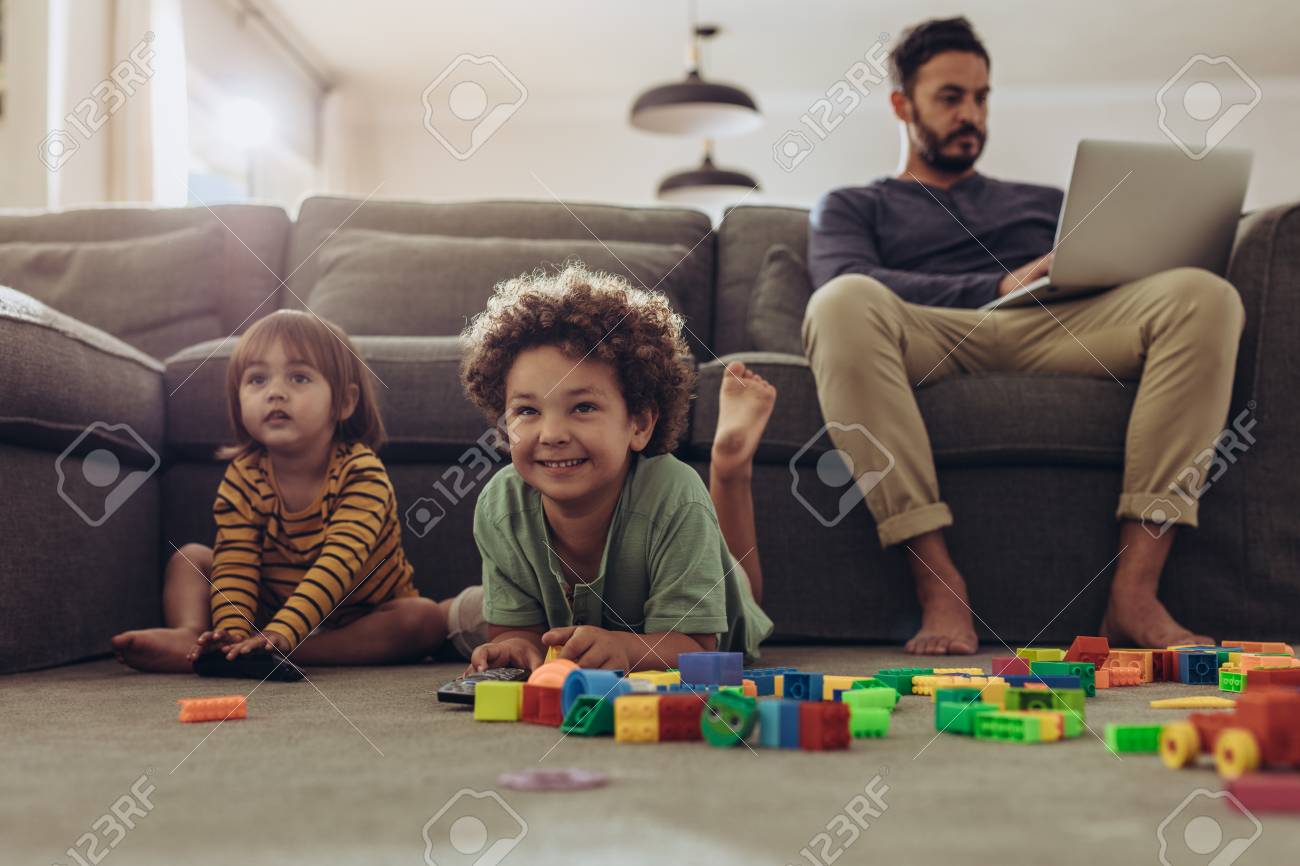 Smiling kids playing with building blocks and watching television at home. - 116176059 Smiling kids playing with building blocks and watching television at home. - 116176059